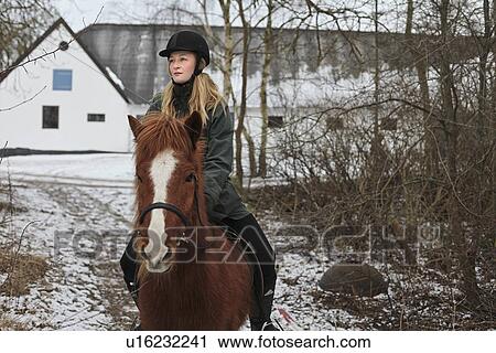 Stock Image - Woman riding horse in snow. Fotosearch