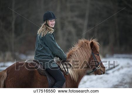 Stock Image - Woman riding horse in snow. Fotosearch