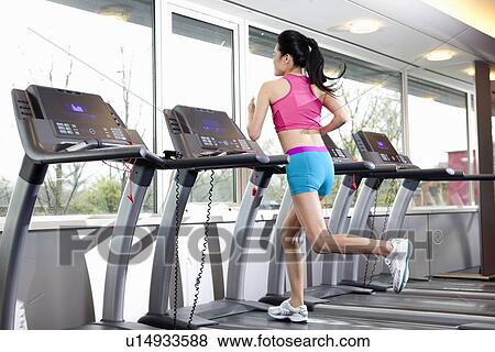 Stock Photo - Woman running on treadmill in gym. Fotosearch