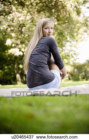 Stock Photo - Woman sitting on blanket in park. Fotosearch