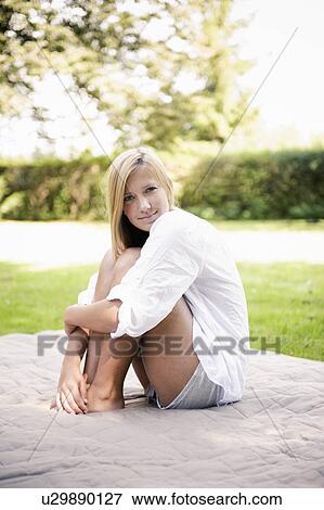 Woman sitting on blanket in park View Large Photo Image Stock Photo - Woman sitting on blanket in park. Fotosearch