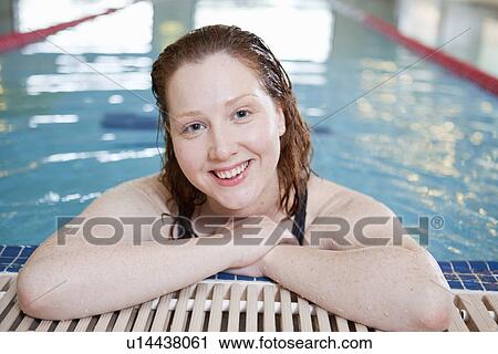 Stock Image - Woman smiling in indoor pool. Fotosearch