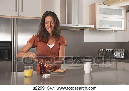 Woman spreading jam on toast in kitchen View Large Photo Image Stock Photo - Woman spreading jam on toast in kitchen. Fotosearch