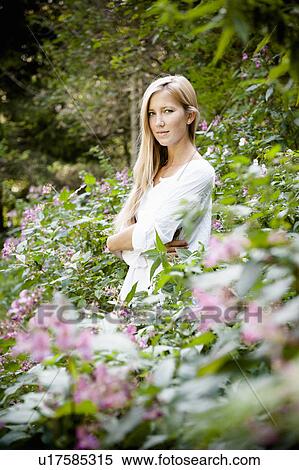 Stock Photography - Woman standing in flower bushes. Fotosearch