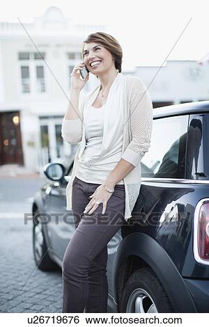 Woman talking on cell phone by car View Large Photo Image Stock Photograph - Woman talking on cell phone by car. Fotosearch