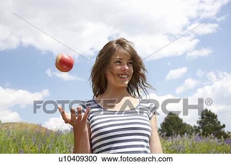 Woman tossing apple outdoors View Large Photo Image Stock Image - Woman tossing apple outdoors. Fotosearch