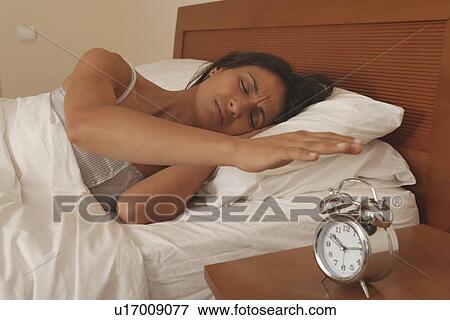 Woman turning off alarm clock View Large Photo Image Stock Photo - Woman turning off alarm clock. Fotosearch