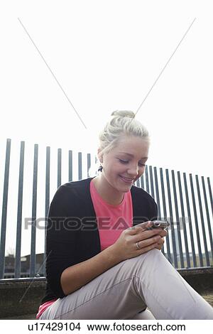 Woman using cell phone on city street View Large Photo Image Picture - Woman using cell phone on city street. Fotosearch