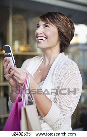Stock Image - Woman using cell phone on city street. Fotosearch