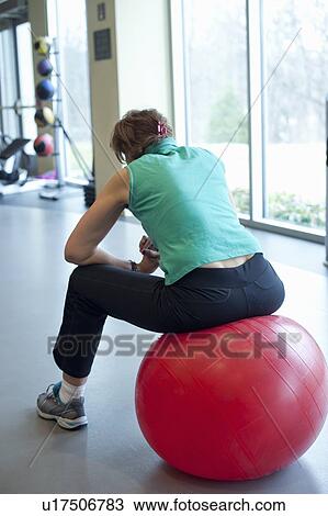 Stock Image - Woman using exercise ball in gym. Fotosearch