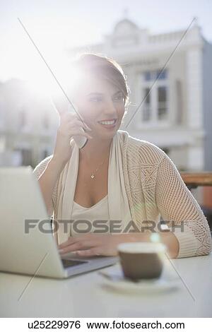 Woman using laptop at sidewalk cafe View Large Photo Image Stock Photograph - Woman using laptop at sidewalk cafe. Fotosearch