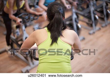 Stock Image - Woman using spin machine in gym. Fotosearch