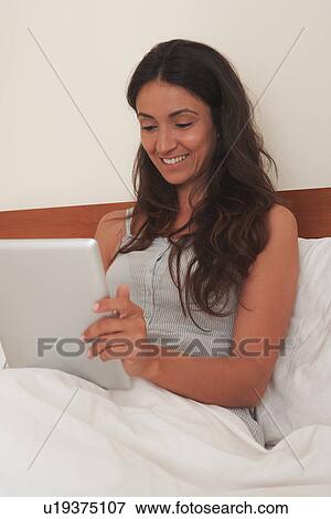 Woman using tablet computer in bed View Large Photo Image Stock Photo - Woman using tablet computer in bed. Fotosearch