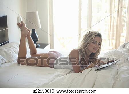 Stock Photo - Woman using tablet computer in bed. Fotosearch