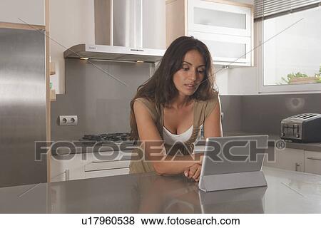 Woman using tablet computer in kitchen View Large Photo Image Stock Photo - Woman using tablet computer in kitchen. Fotosearch
