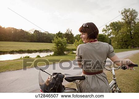Stock Photo - Woman walking bicycle on rural road. Fotosearch