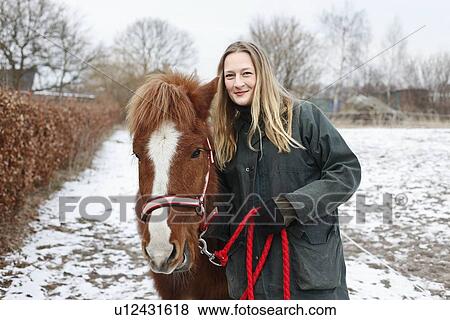 Stock Photo - Woman walking horse on snowy path. Fotosearch