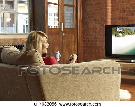 Woman watching television on sofa View Large Photo Image Stock Photograph - Woman watching television on sofa. Fotosearch