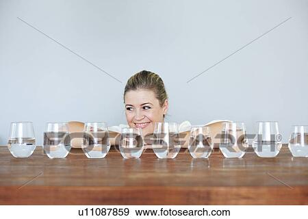 Woman with glasses of water on table View Large Photo Image Stock Photo - Woman with glasses of water on table. Fotosearch