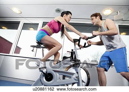 Stock Image - Woman working with trainer in gym. Fotosearch