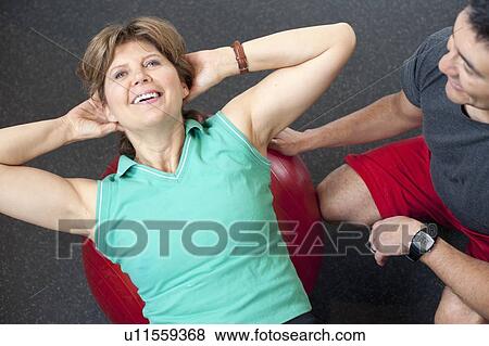 Stock Photo - Woman working with trainer in gym. Fotosearch