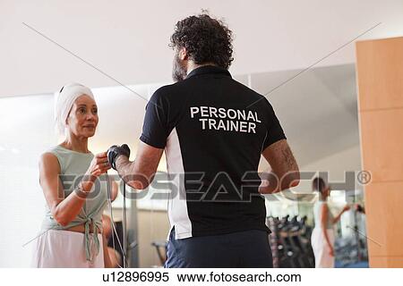 Stock Photography - Woman working with trainer in gym. Fotosearch