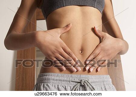 Stock Photograph - Womans hands cupping her bellybutton. Fotosearch