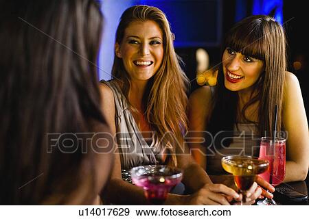 Stock Photo - Women having drinks together at bar. Fotosearch