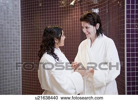 Stock Image - Women in bathrobes talking in shower. Fotosearch
