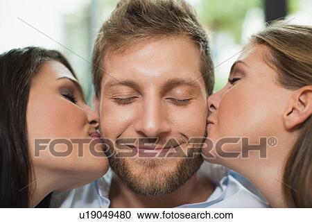 Stock Image - Women kissing smiling mans cheeks. Fotosearch