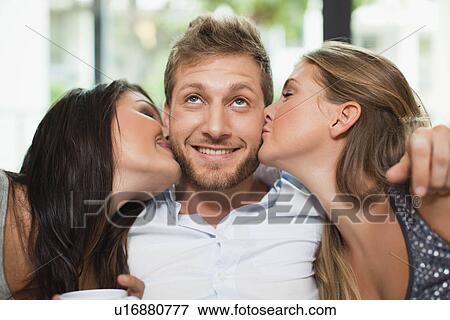 Stock Photo - Women kissing smiling mans cheeks. Fotosearch