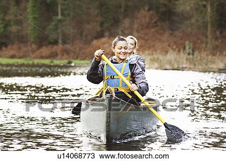Women rowing canoe on still lake View Large Photo Image Stock Image - Women rowing canoe on still lake. Fotosearch
