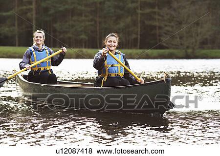 Women rowing canoe on still lake View Large Photo Image Stock Photo - Women rowing canoe on still lake. Fotosearch