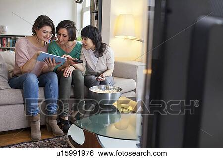 Stock Photograph - Women using tablet computer on sofa. Fotosearch