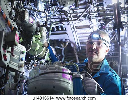 Worker adjusting airplane machinery View Large Photo Image Picture - Worker adjusting airplane machinery. Fotosearch