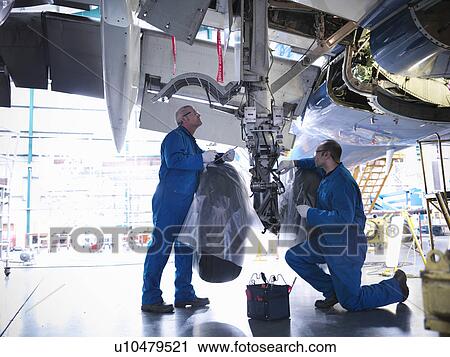 Stock Image - Worker adjusting airplane machinery. Fotosearch