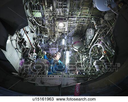 Stock Image - Worker adjusting airplane machinery. Fotosearch