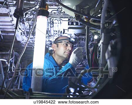 Stock Image - Worker adjusting airplane machinery. Fotosearch