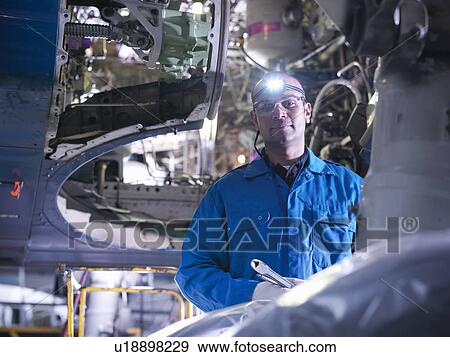 Stock Photo - Worker adjusting airplane machinery. Fotosearch