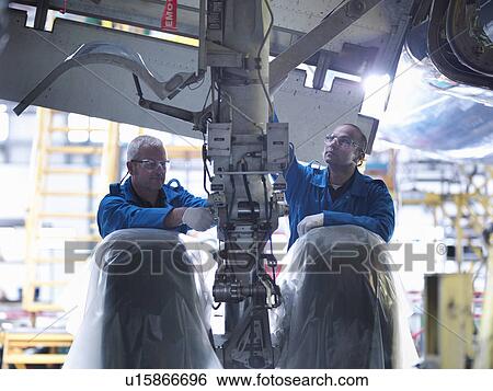 Stock Photograph - Worker adjusting airplane machinery. Fotosearch