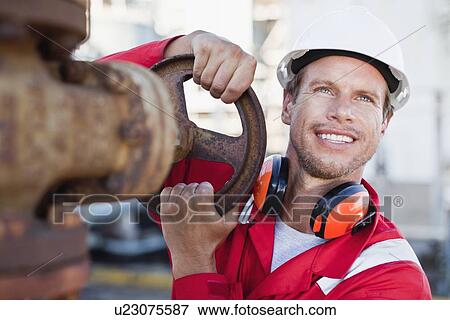 Stock Photo - Worker adjusting gauge at chemical plant. Fotosearch