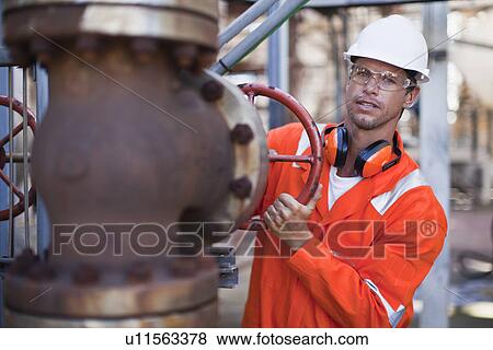 Worker adjusting gauge at oil refinery View Large Photo Image Stock Photo - Worker adjusting gauge at oil refinery. Fotosearch