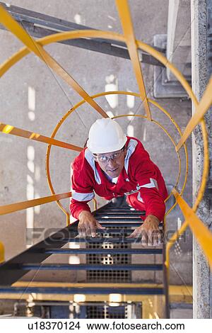 Worker climbing ladder at oil refinery View Large Photo Image Picture - Worker climbing ladder at oil refinery. Fotosearch