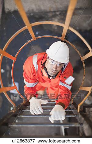 Worker climbing ladder at oil refinery View Large Photo Image Stock Photo - Worker climbing ladder at oil refinery. Fotosearch