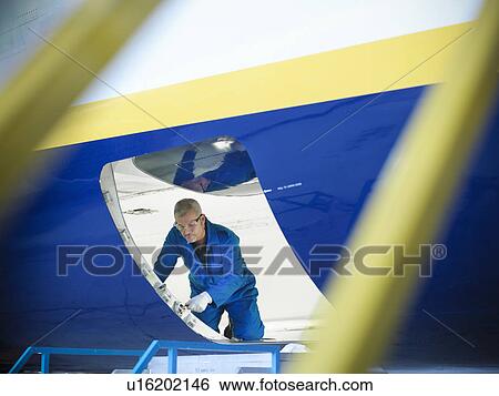 Stock Photograph - Worker examining airplane door. Fotosearch