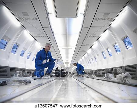 Stock Photo - Worker examining empty airplane. Fotosearch