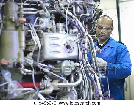 Stock Image - Worker examining machinery on drums. Fotosearch