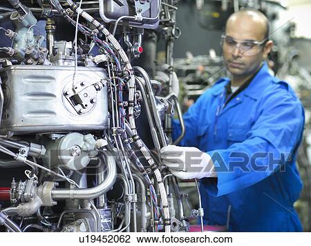 Stock Image - Worker examining machinery on drums. Fotosearch