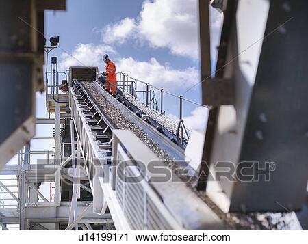 Worker examining stones on conveyor belt View Large Photo Image Stock Image - Worker examining stones on conveyor belt. Fotosearch