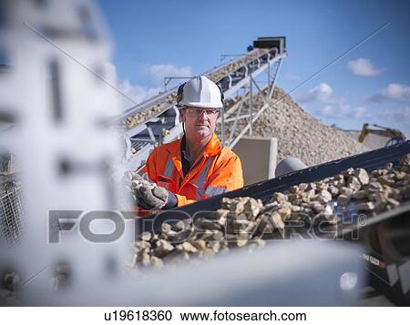 Worker examining stones on conveyor belt View Large Photo Image Stock Image - Worker examining stones on conveyor belt. Fotosearch
